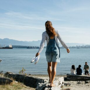 A woman walking on a log at Spanish Banks Beach in Vancouver