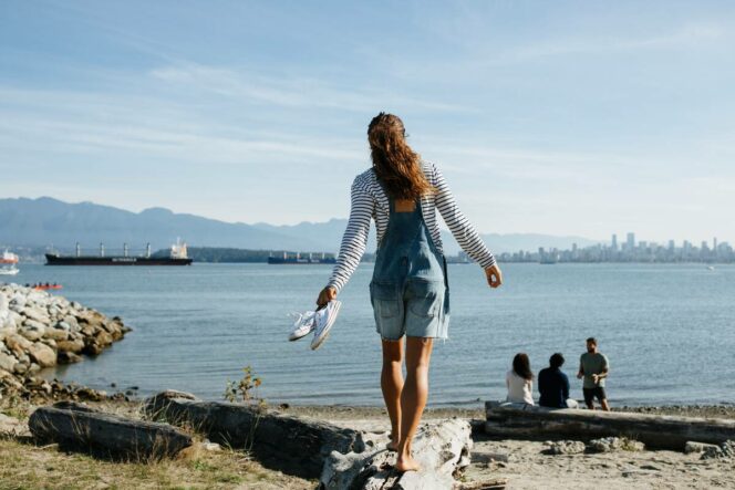 A woman walking on a log at Spanish Banks Beach in Vancouver