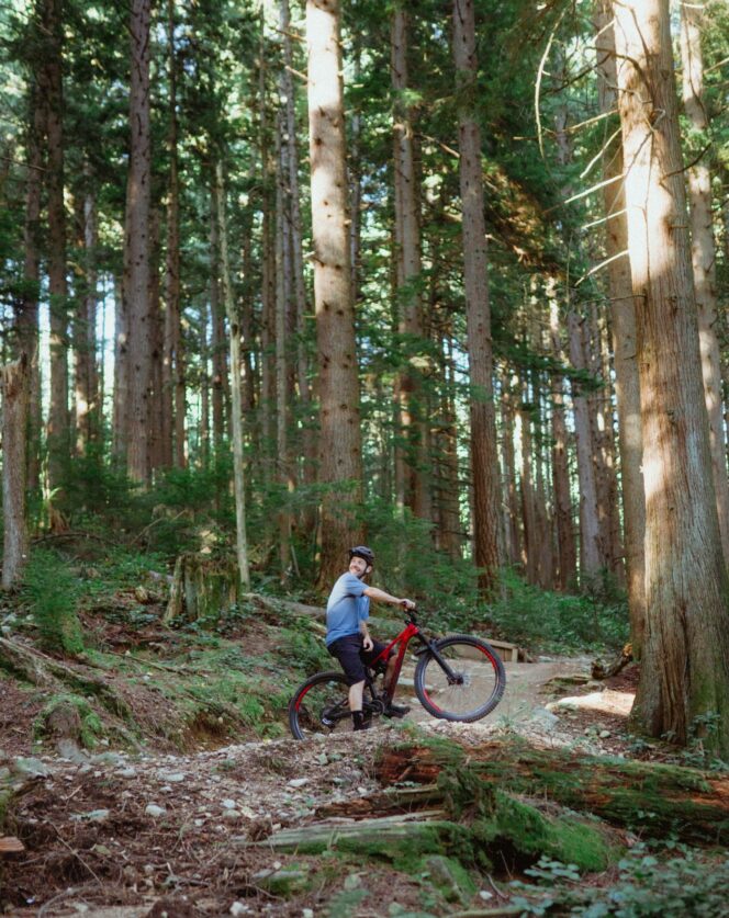 A person on a red bike poses on a mountain bike trail on the North Shore in Vancouver