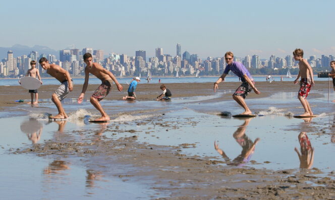 A group of skimboarders in Vancouver with the skyline in the background