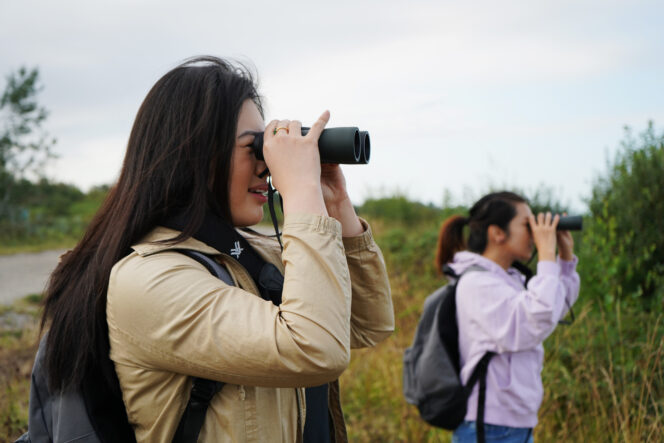 Two people use binoculars to watch birds in Terra Nova Rural Park near Vancouver