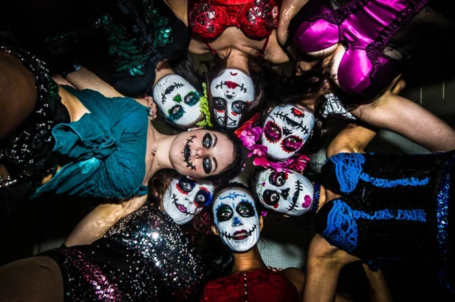 A group of performers in Day of the Dead face paint pose at the Parade of Lost Souls